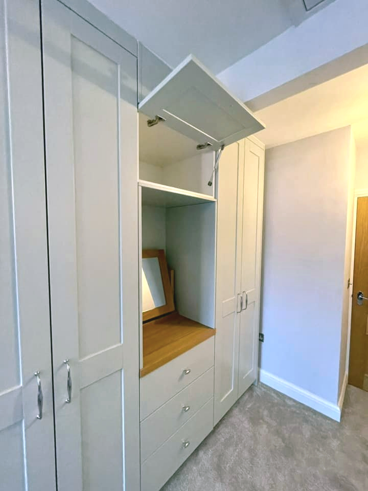 Fitted wardrobe with built in vanity desk and open cupboard door