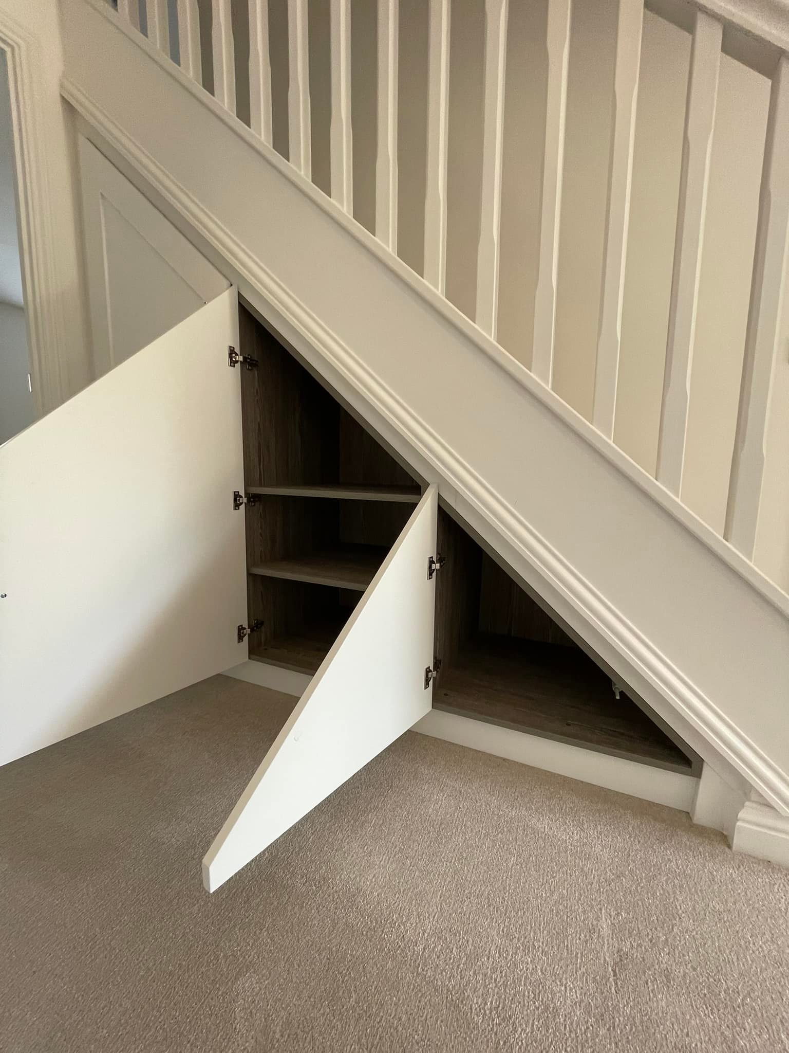 White understairs storage with open doors showing shelving